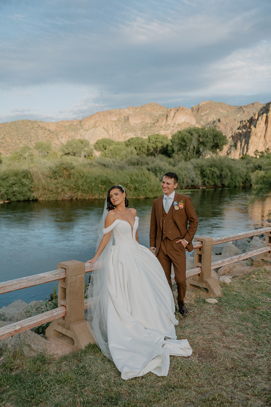 A bride and groom taking photos by a pond
