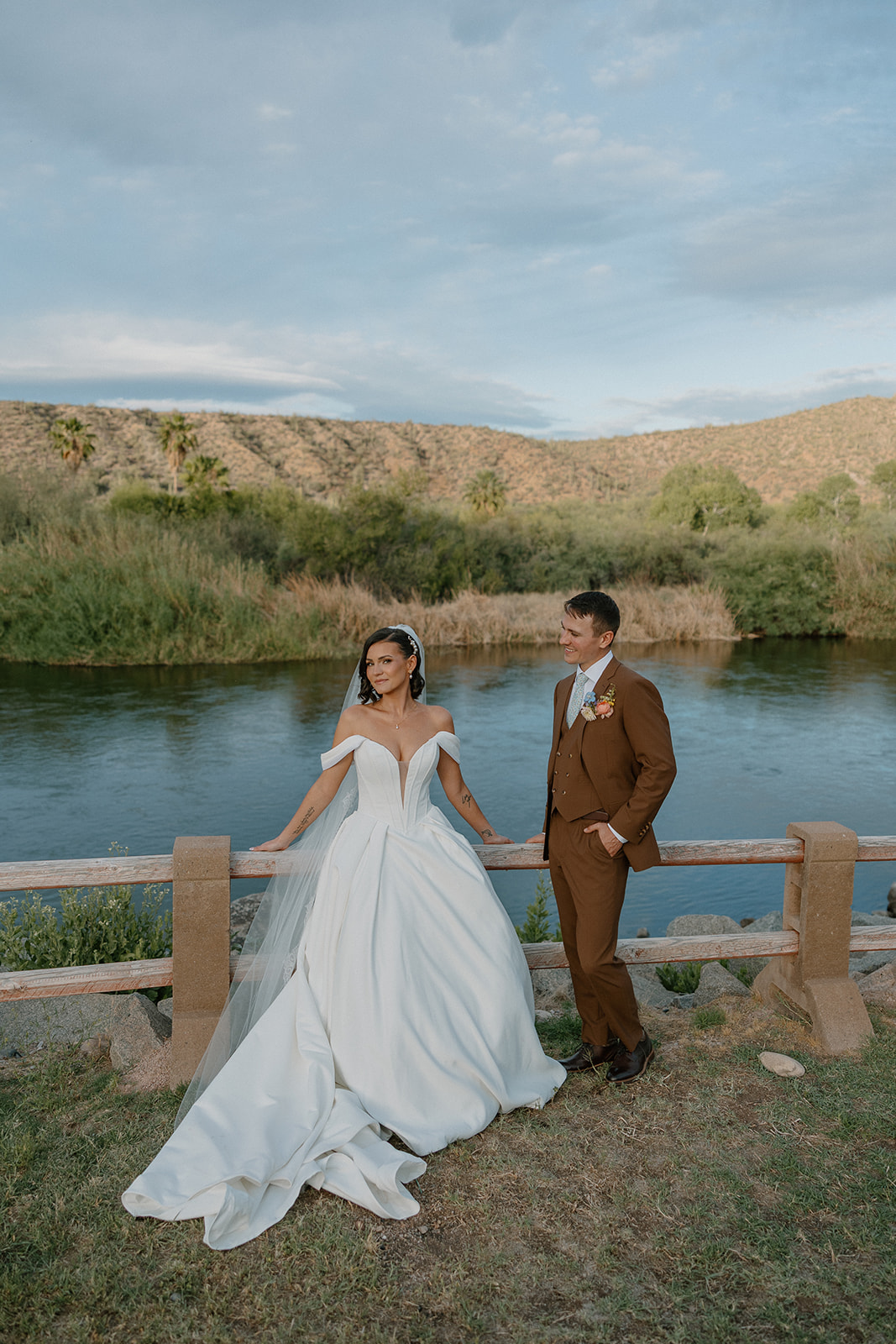 A bride and groom taking photos by a pond