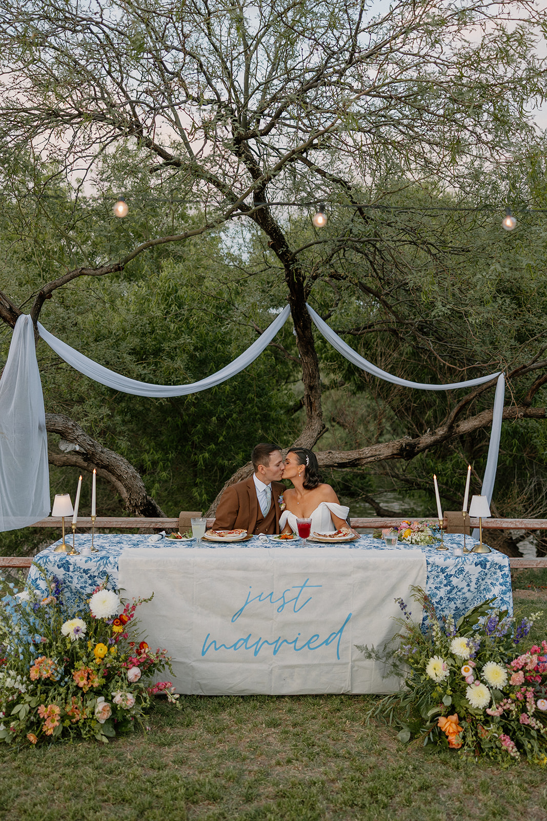 A bride and groom kissing at their sweetheart table