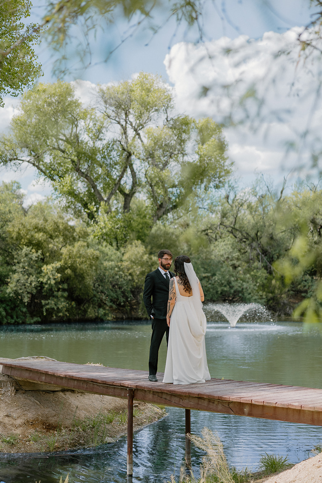 A bride and groom posing for photos by the pond at Tanque Verde Ranch