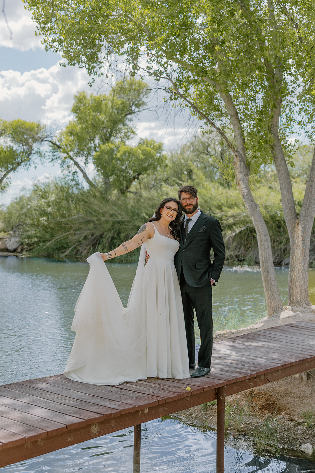A bride and groom posing for photos by the pond at Tanque Verde Ranch