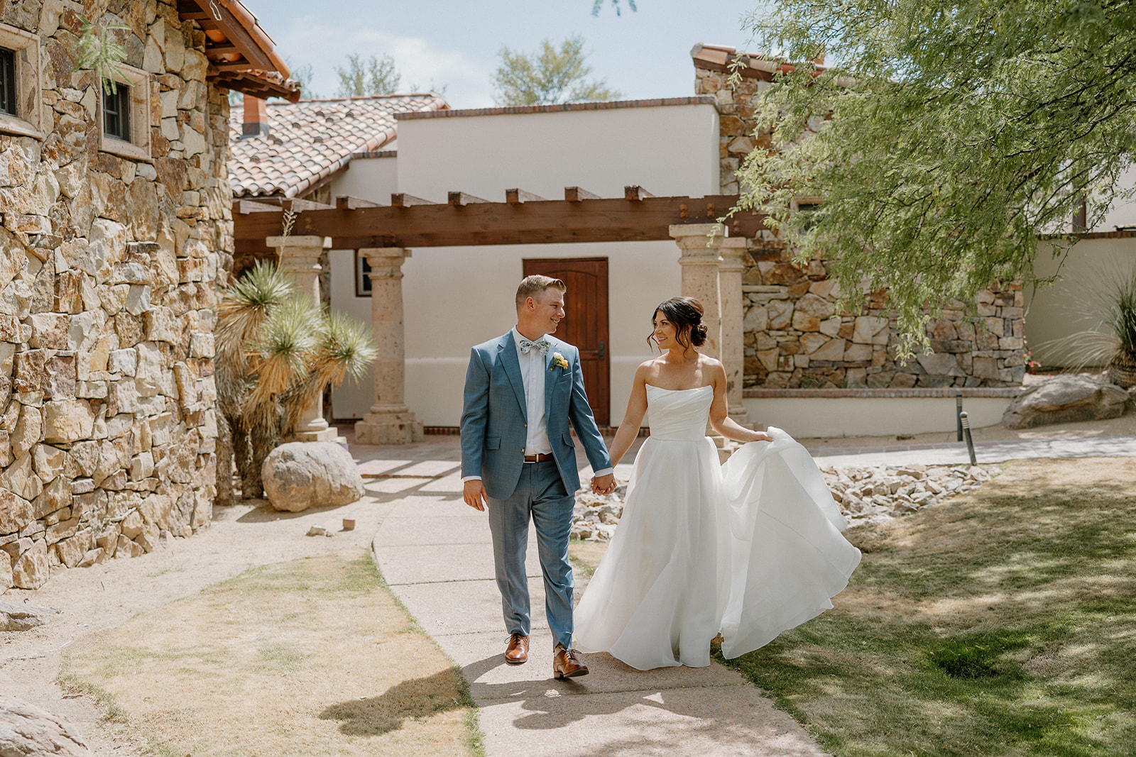 A bride and groom walking through their backyard wedding