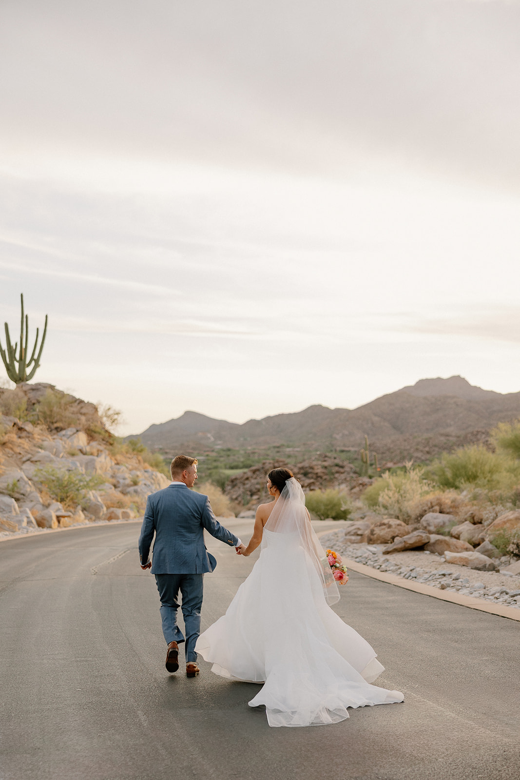 A bride and groom taking sunset wedding photos on a street