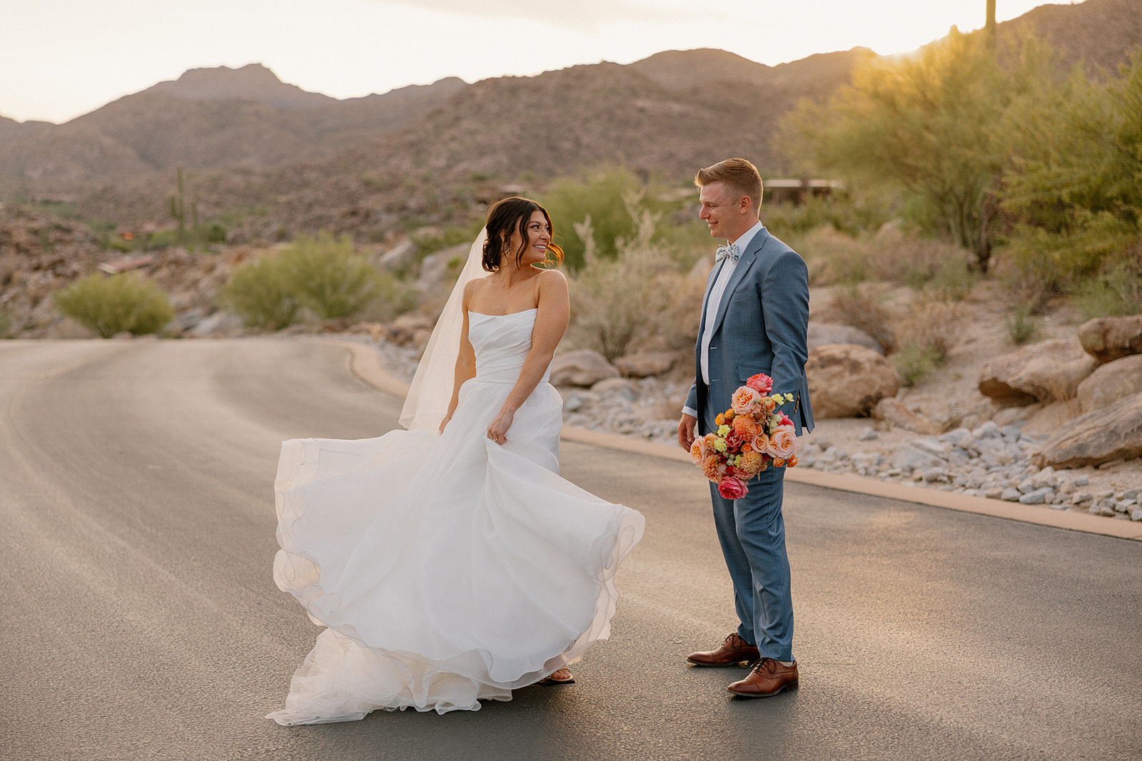 A bride and groom posing for wedding photos on a street