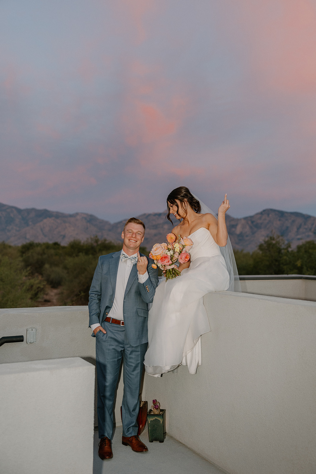 A bride and groom taking sunset wedding photos on a rooftop