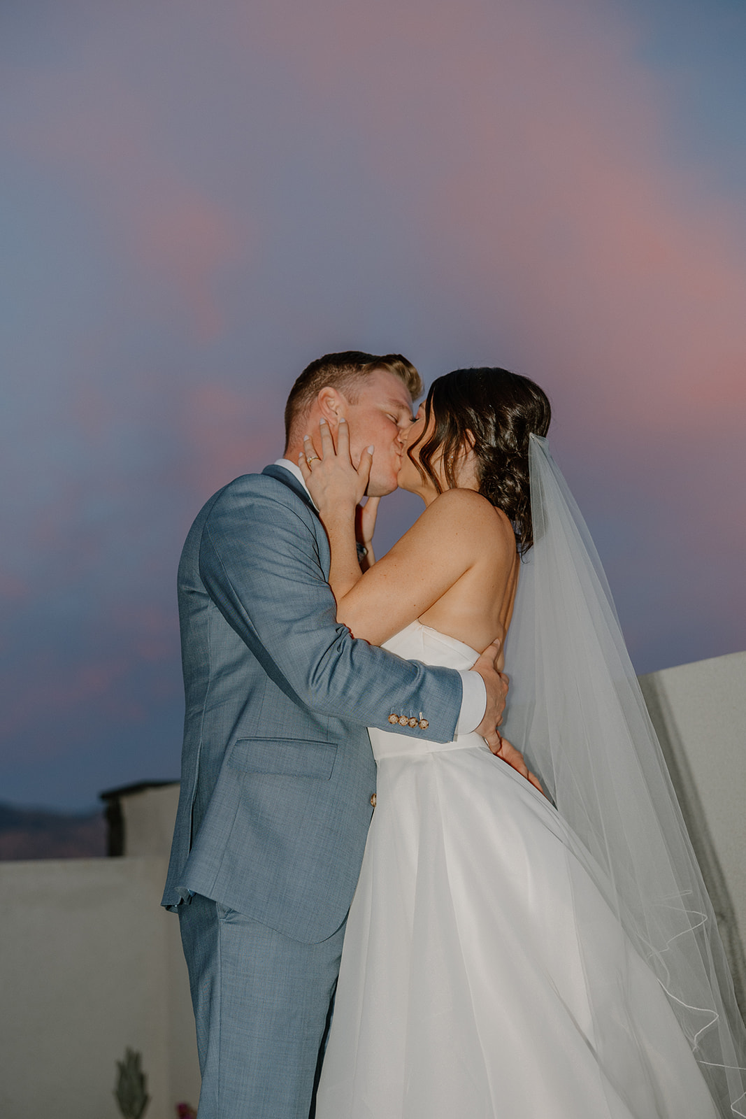 A bride and groom taking sunset wedding photos on a rooftop