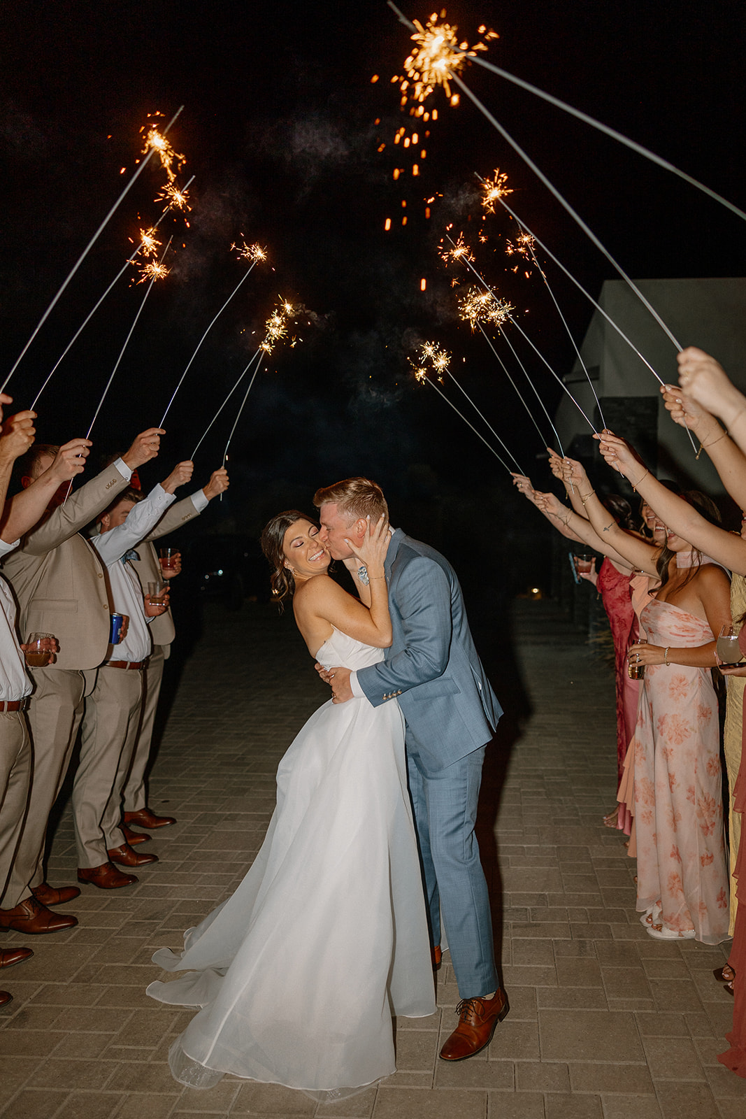 A bride and groom kissing during their sparkler exit