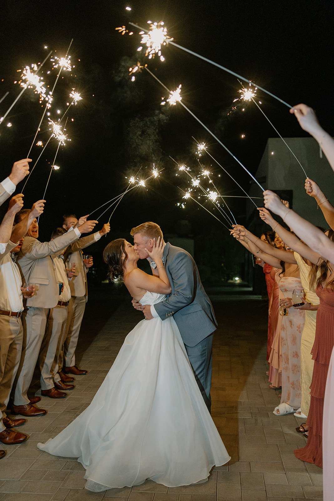 A bride and groom kissing during their sparkler exit