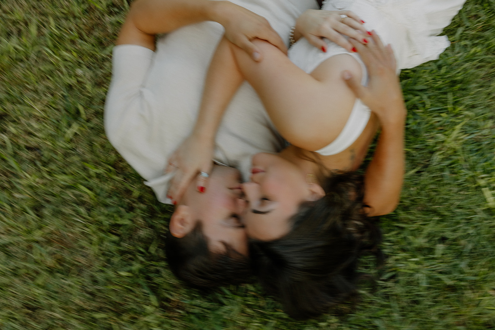 A blurry engagement photo of a couple lying in the grass