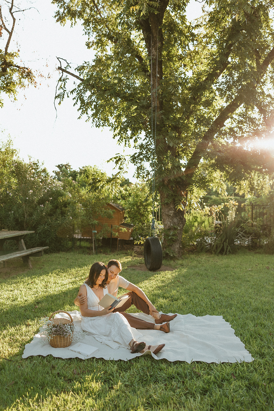 A couple taking garden engagement photos with a picnic setup