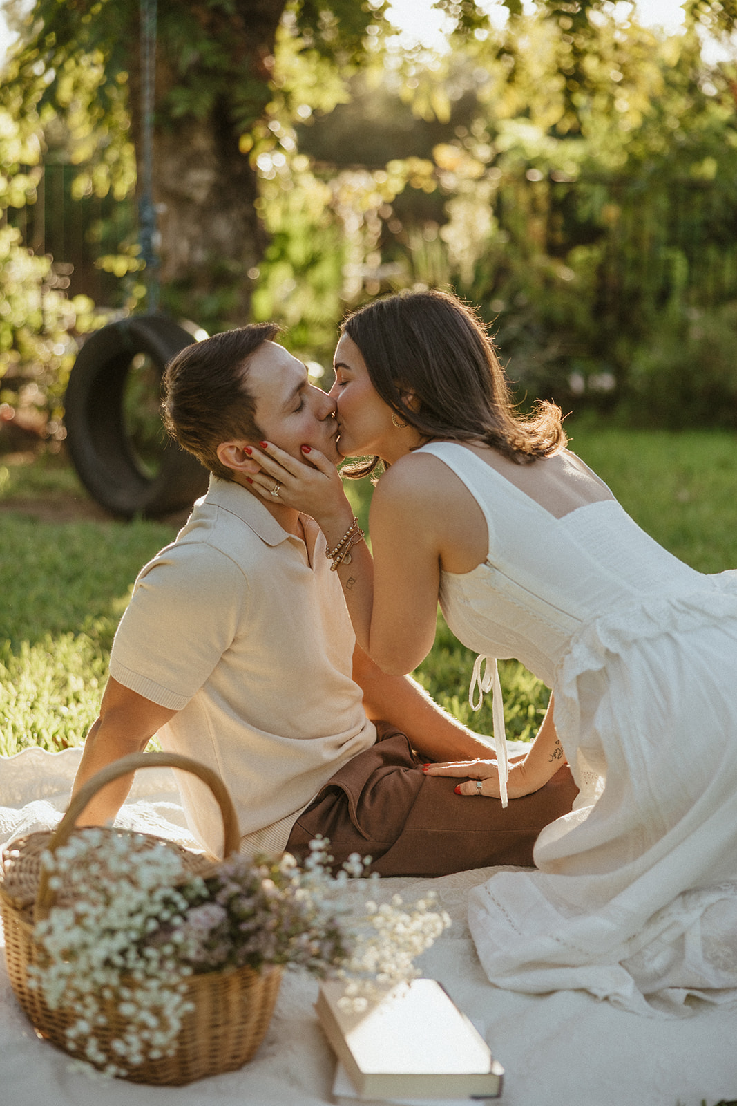 A couple kissing at their picnic engagement photos in a garden