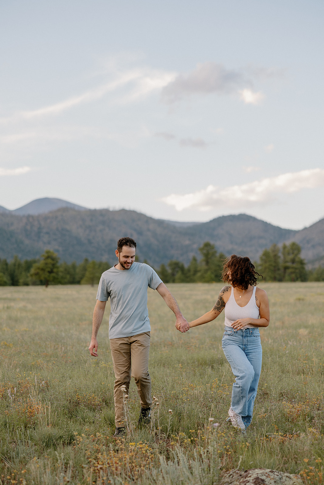 A couple running through a field at their engagement photo location