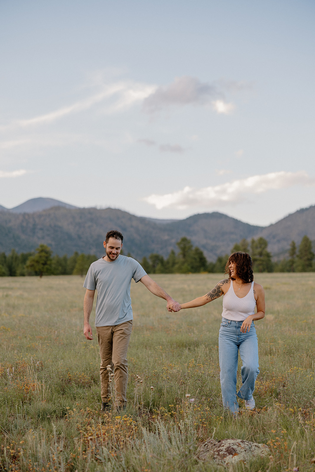 A couple running through a field at their engagement photo location