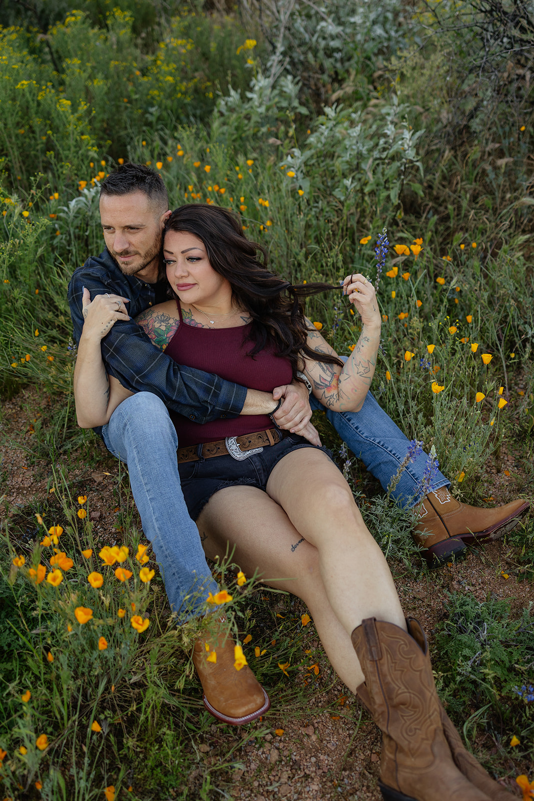 A couple sitting on the ground for engagement photos at Bartlett Lake in Arizona