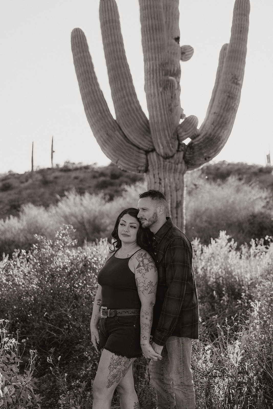 A couple posing for engagement photos in a field at Bartlett Lake in Arizona