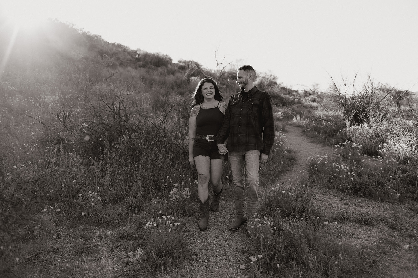 A black and white photo of a couple walking through a field at Bartlett Lake