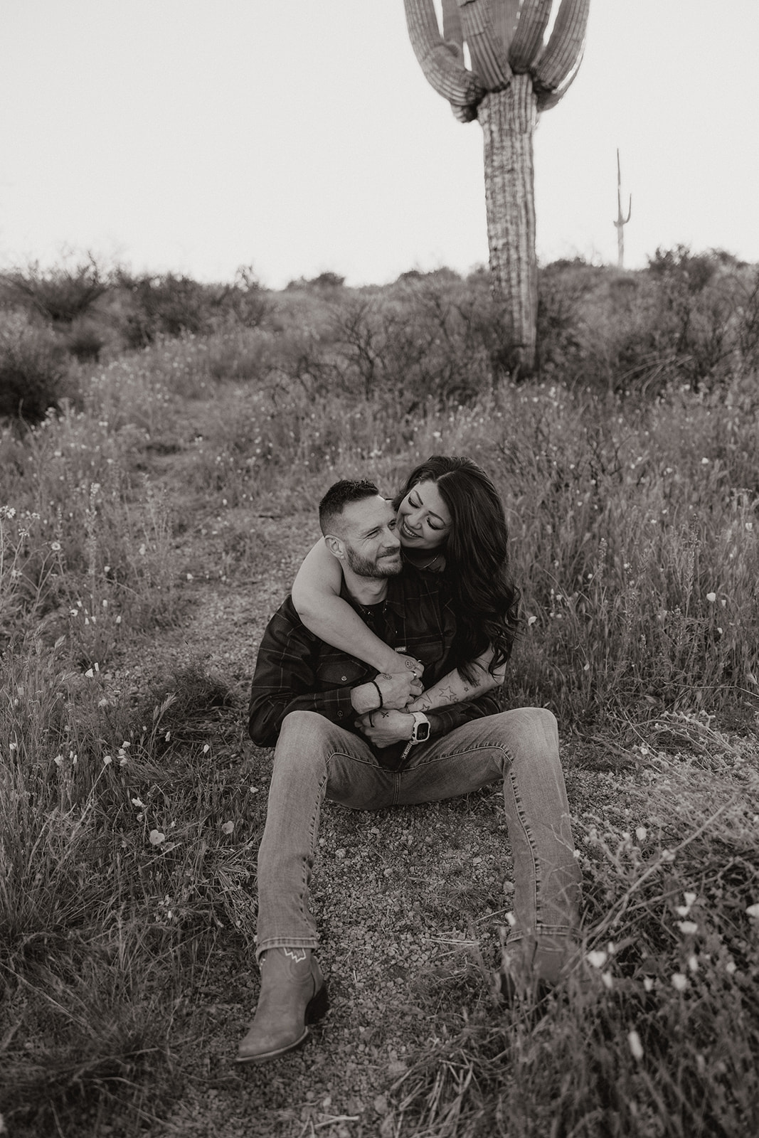 A couple posing for engagement photos in a field at Bartlett Lake in Arizona
