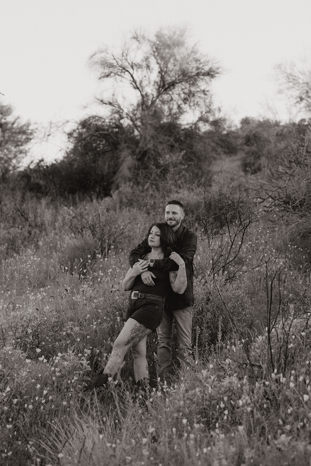 A couple posing for engagement photos in a field at Bartlett Lake in Arizona