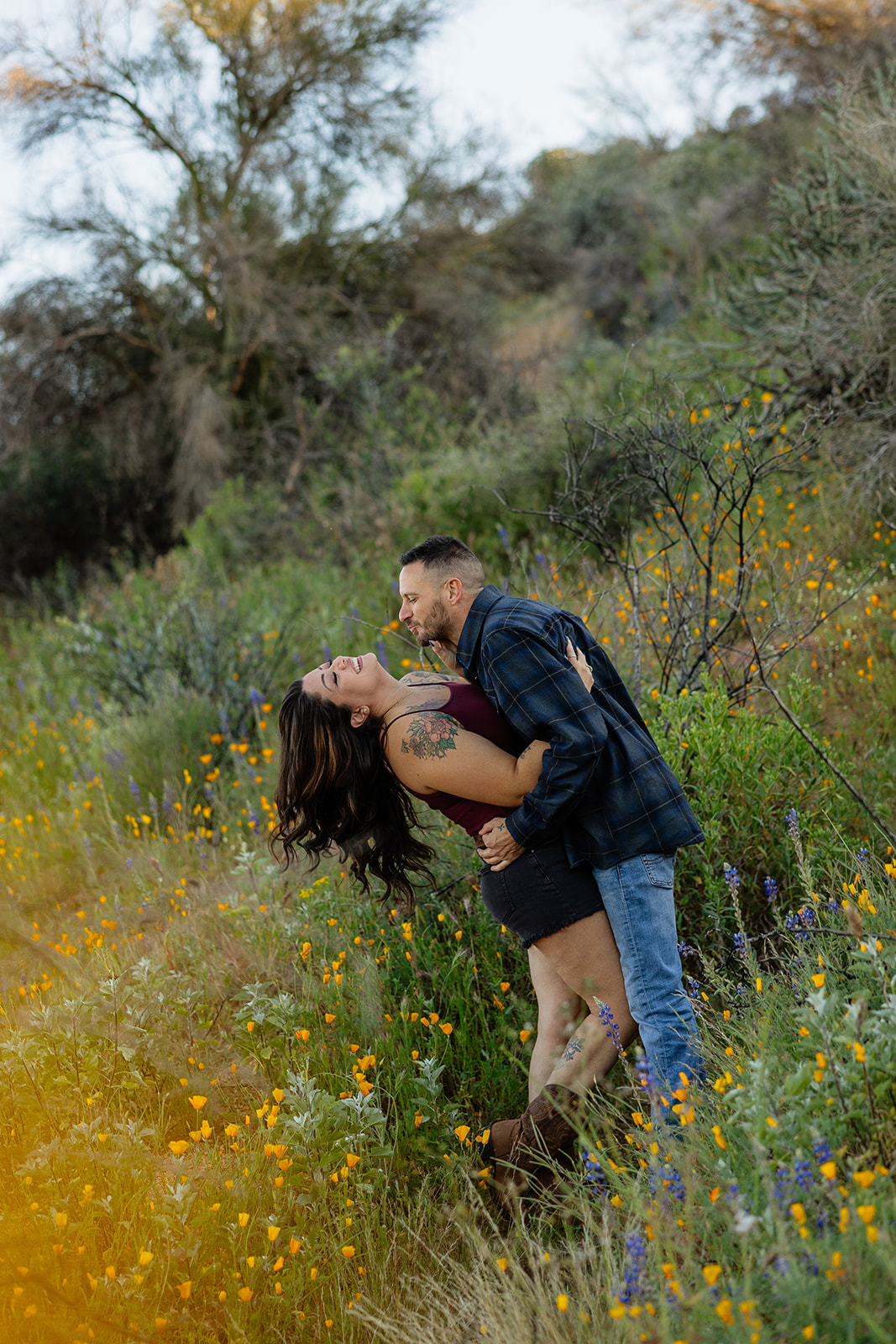 A couple posing for engagement photos in the wildflower fields at Bartlett Lake in Arizona