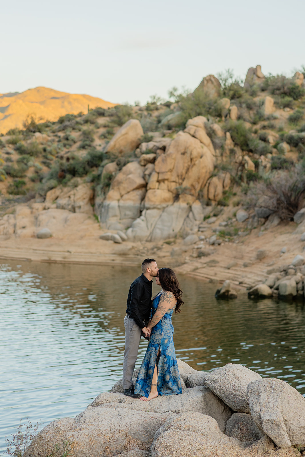 a man kissing his fiancee on the forehead during lake engagement photos