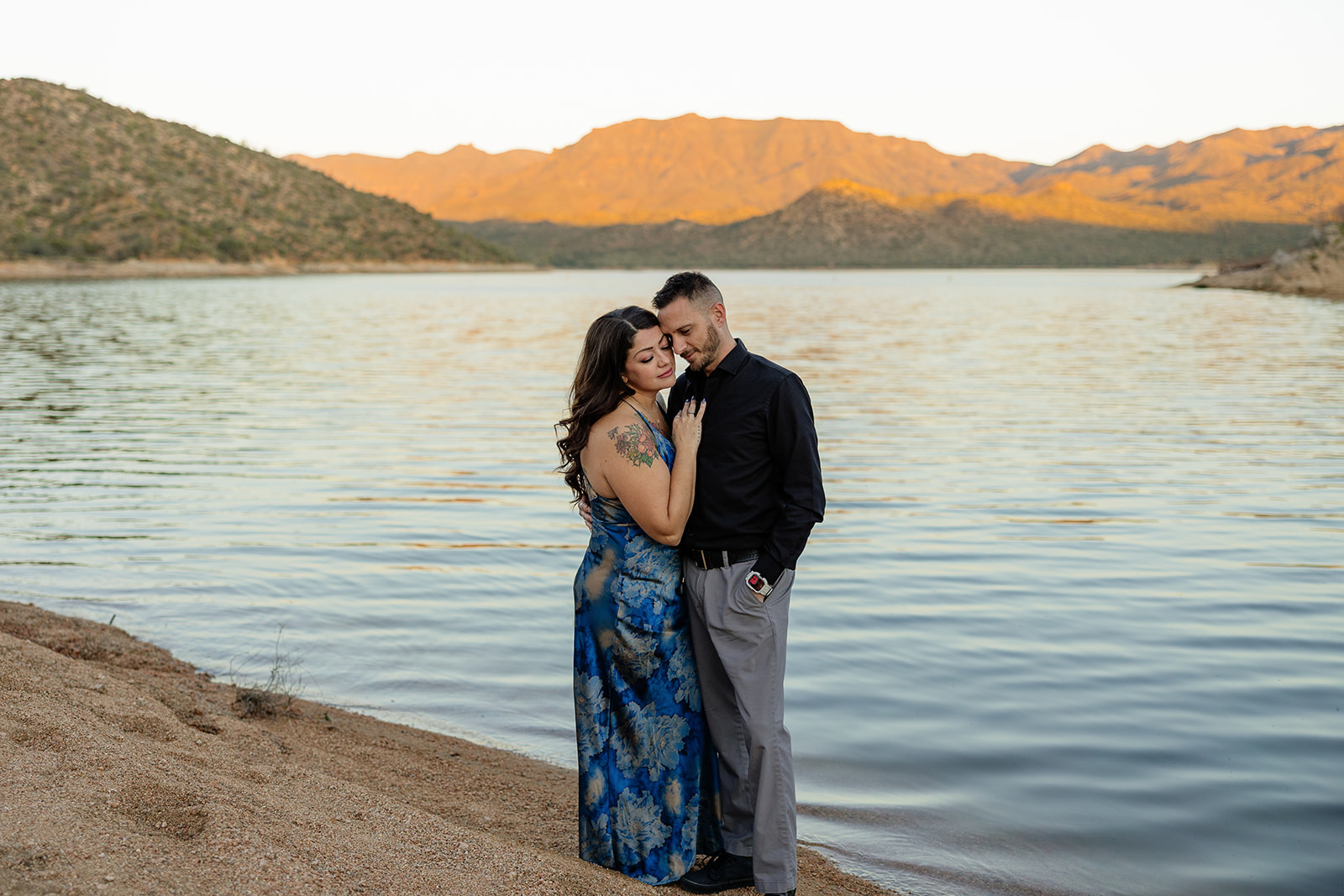A couple posing for engagement photos in front of a lake